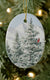 The Pure White oval ceramic ornament against a Christmas tree background.