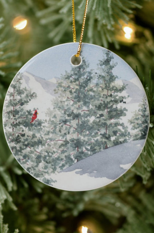 The Pure White circular ceramic ornament against a Christmas tree background.