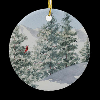 Close up of Pure White round ceramic ornament. It features a snowy landscape with a red cardinal perched in a tree.
